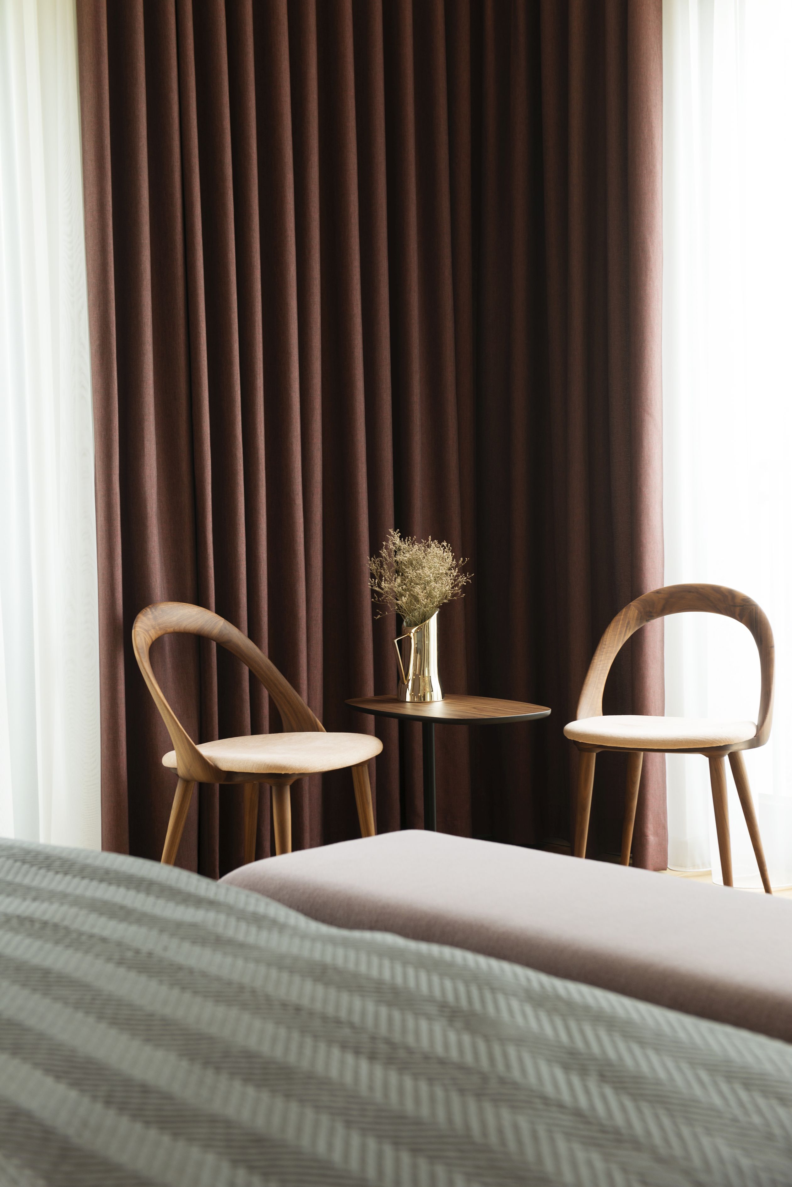 Kolor zasłon podkreśla drewno orzechowe na meblach.